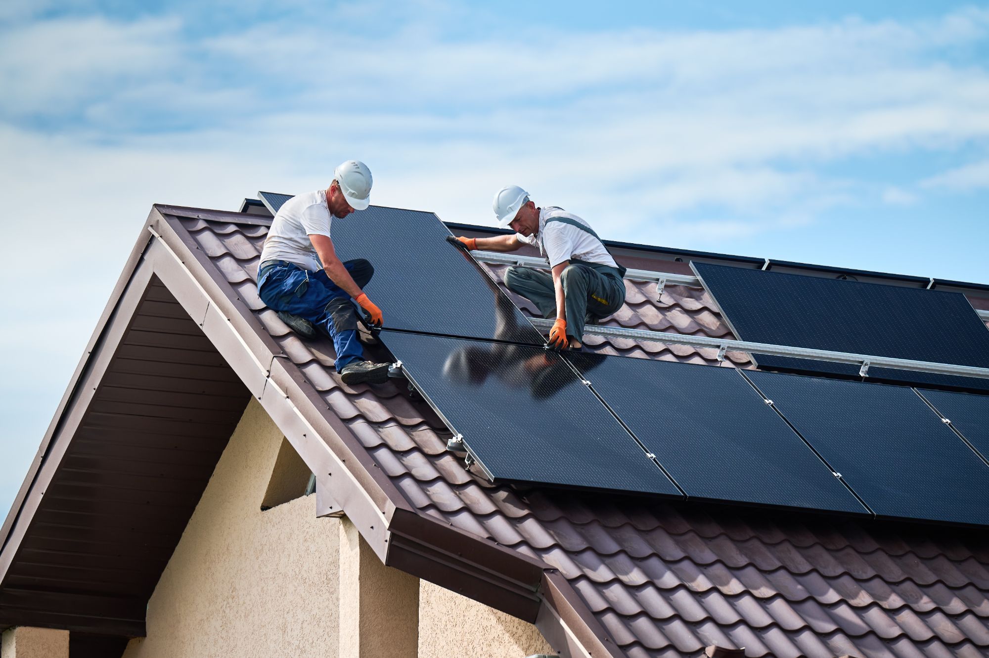 Installateurs posant des capteurs solaires hybrides en toiture